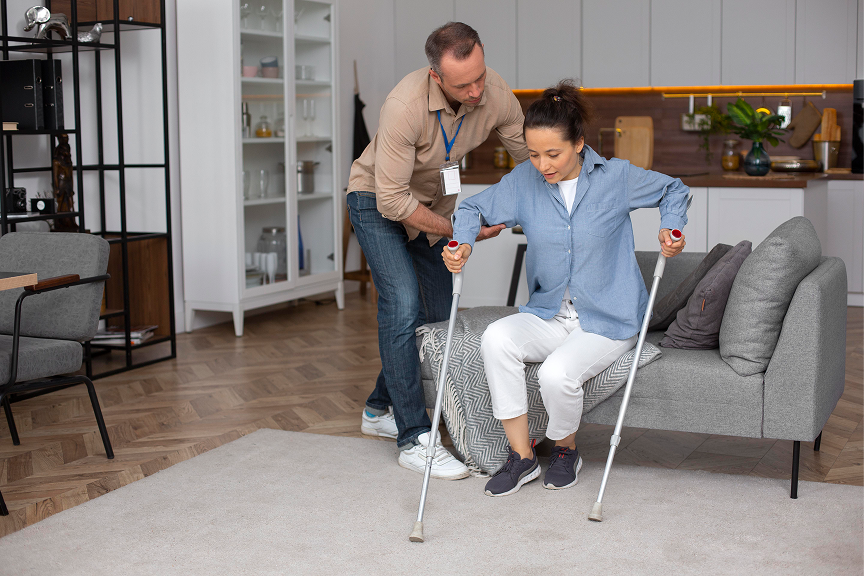 Un bénévole aide une personne à béquille à se lever du sofa